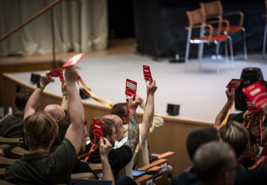 Uppsträckta armar och händer som håller i röstkort på Elektrikernas kongress