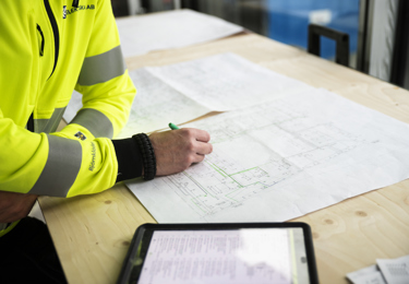 En hand som håller i en penna och ritar på en ritning