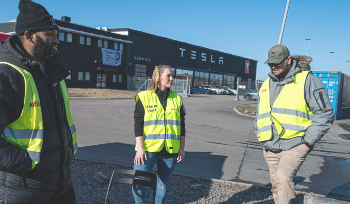 Strejkvakter i varselvästar utanför en Tesla-verkstad