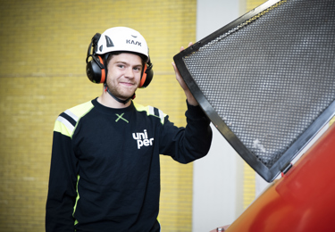 Elektriker med en hjälm på huvudet som ler och tittar in i kameran