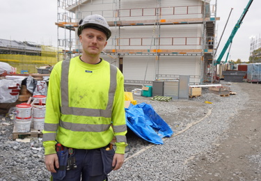 En medlem i Elektrikerna som står vid ett bygge och som jobbar på ackord