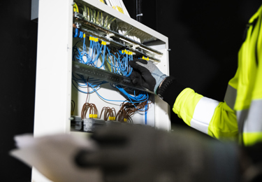 Hand som hanterar sladdar i ett elskåp