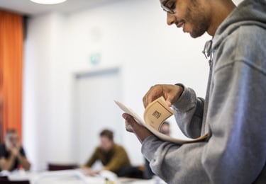 Förtroendevald medlem i Elektrikerna delar ut papper till deltagare på ett möte