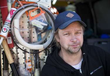 Elektriker med keps på huvudet som tittar in i kameran och ler