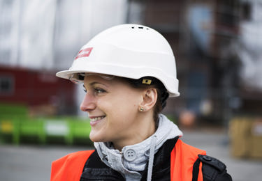 Leende elektriker i hjälm med Elektrikernas logotyp på