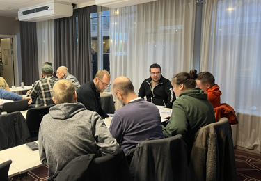 Medlemmar i Elektrikerna som tillsammans sitter runt ett bord och pratar