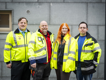 Fyra elektriker som står bredvid varandra iklädda gula varseljackor