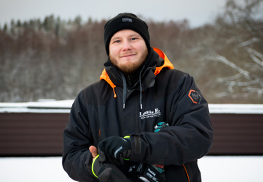 Elektriker som står ute i en trädgård täckt av snö