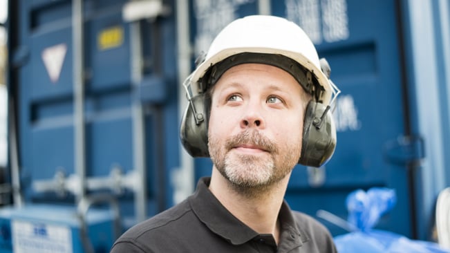 Elektriker med hjälm och hörselkåpor på huvudet som ser undrande ut
