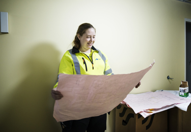 En leende elektriker som håller i och tittar på en ritning