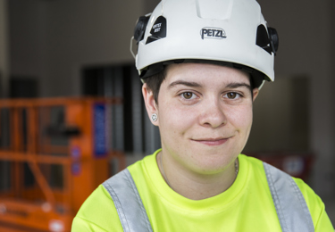 En elektriker som tittar in i kameran och ler.