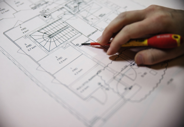 Hand som håller i ett verktyg, som pekar på en ritning