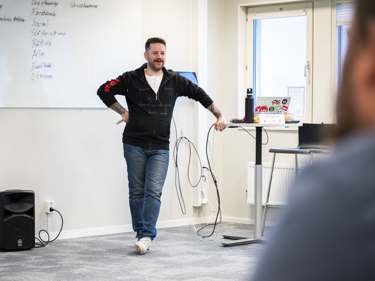 En man i en lokal för undervisning håller i en kurs för deltagande lyssnare.