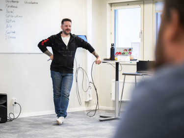 En man i en lokal för undervisning håller i en kurs för deltagande lyssnare.