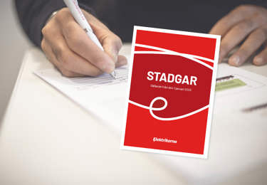 Person som skriver på ett papper i bakgrunden och i förgrunden syns framsidan till Elektrikernas stadgar