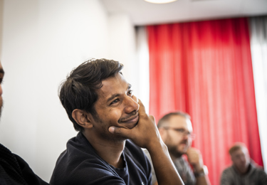 Kvinnlig elektriker i hjälm med hörselkåpor som ler och håller i en skruvdragare