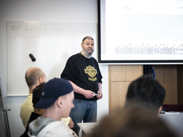 En man i en lokal för undervisning håller i en kurs för deltagande lyssnare.