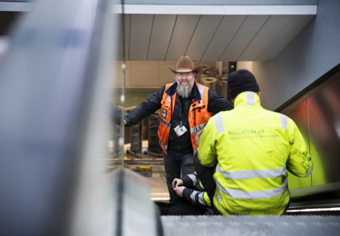 Elektriker i väst som står i en rulltrappa
