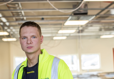 En ung elektriker i varseljacka som befinner sig på ett bygge