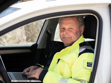 Elektriker sittandes i en bil med en laptop i sitt knä