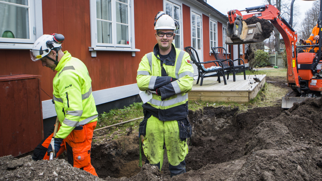 Medlem i Elektrikerna som står med armarna i kors, har på sig varselkläder och befinner sig på en byggarbetsplats