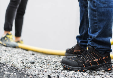 Två par fötter med skor på sig, som står i grus