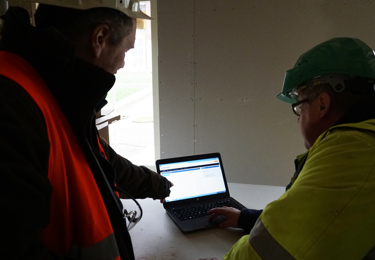 Två elektriker som tittar på en bärbar dator